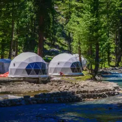 Glamping nad jeziorem: kopuły noclegowe w otoczeniu lasu, blisko rwącej rzeki.