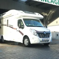 Biała kamperka "Alaska TD" wyjeżdża z hali, gotowa na targi caravaningowe.