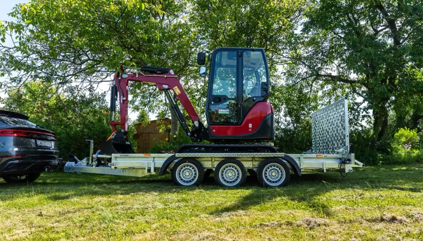 Mini koparka na przyczepie, gotowa do transportu. Posiadanie prawa jazdy na przyczepę ułatwia przewóz takiego sprzętu.