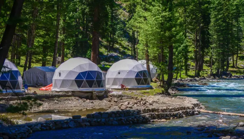 Glamping nad jeziorem: kopuły noclegowe w otoczeniu lasu, blisko rwącej rzeki.