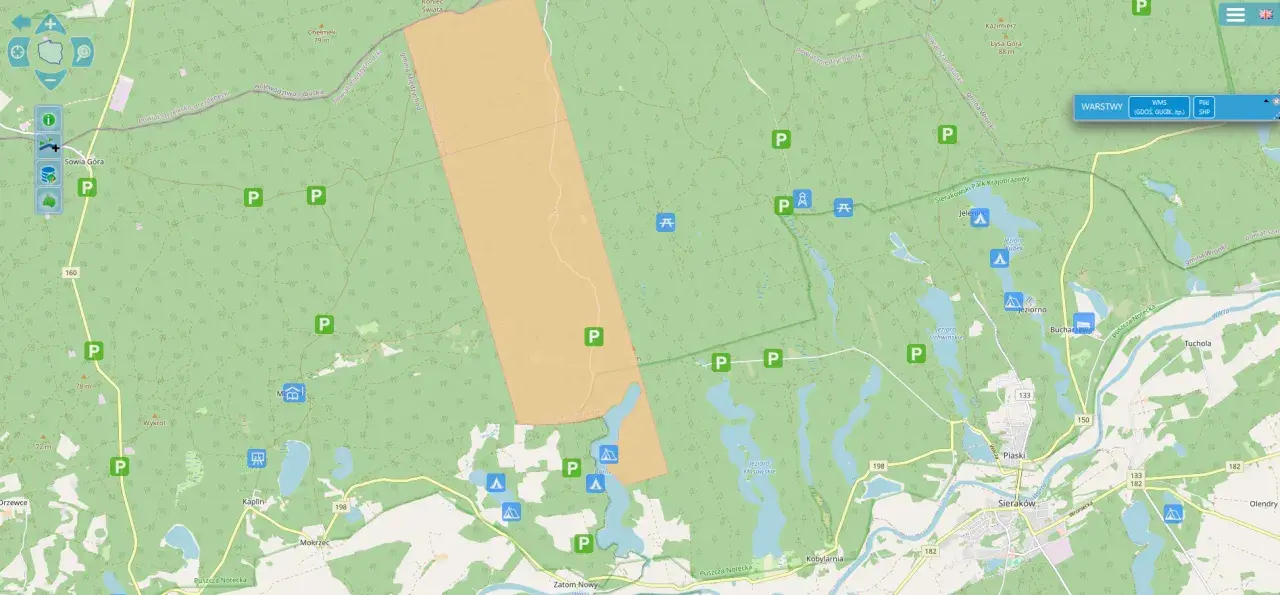 Mapa z zaznaczonymi darmowymi miejscami biwakowymi w lesie, obok jezior i dróg.