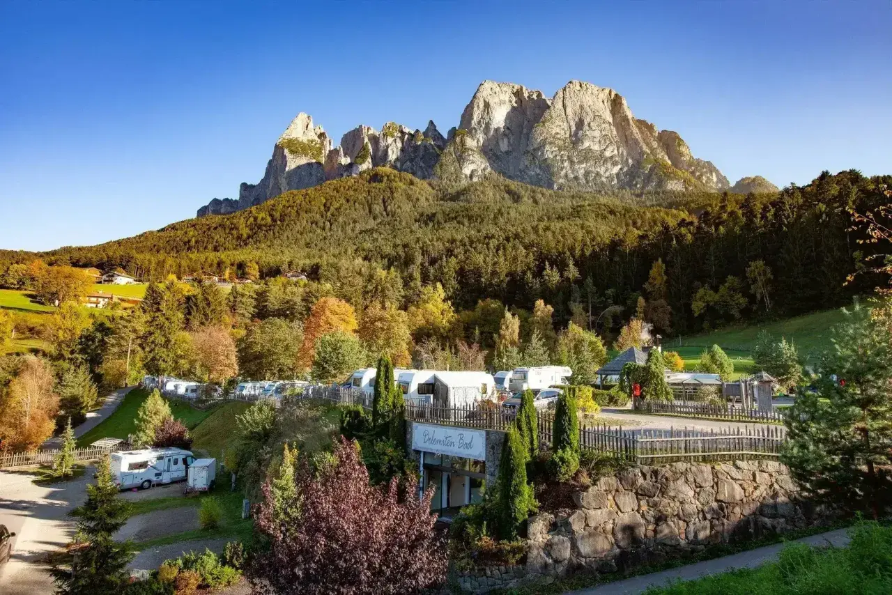 Malowniczy camping Seiser Alm z kamperami i przyczepami pod majestatycznymi szczytami Dolomitów.