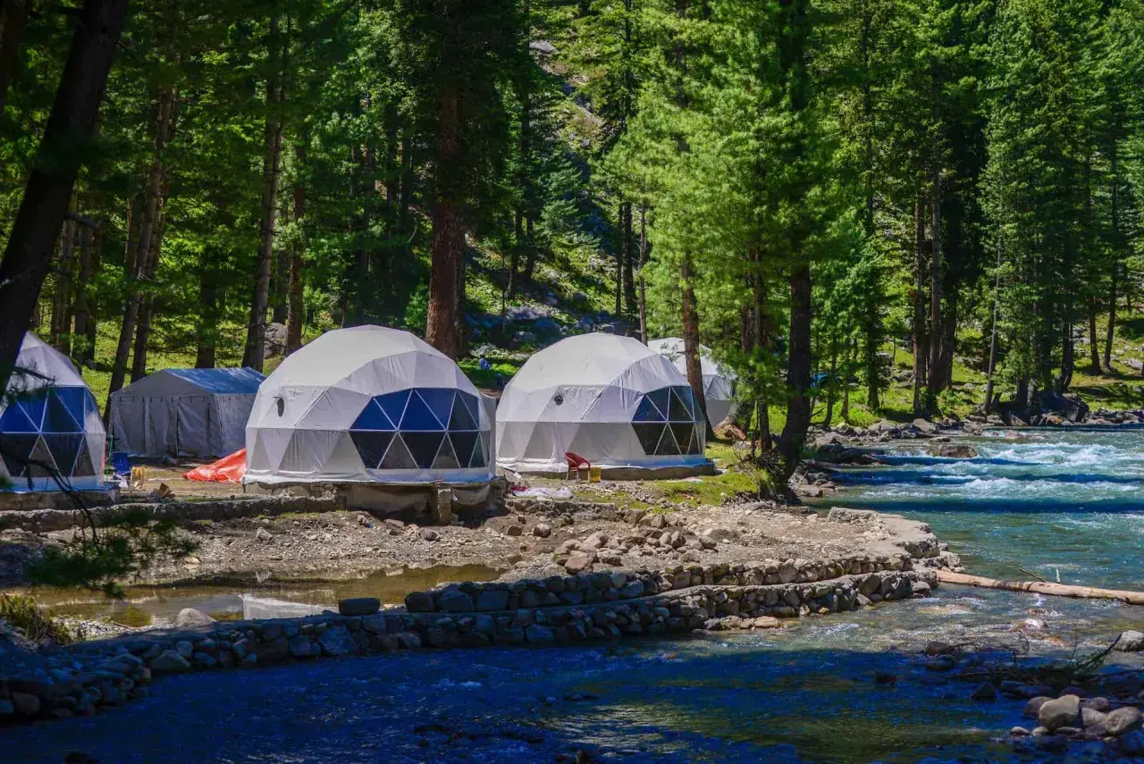 Glamping nad jeziorem: kopuły noclegowe w otoczeniu lasu, blisko rwącej rzeki.