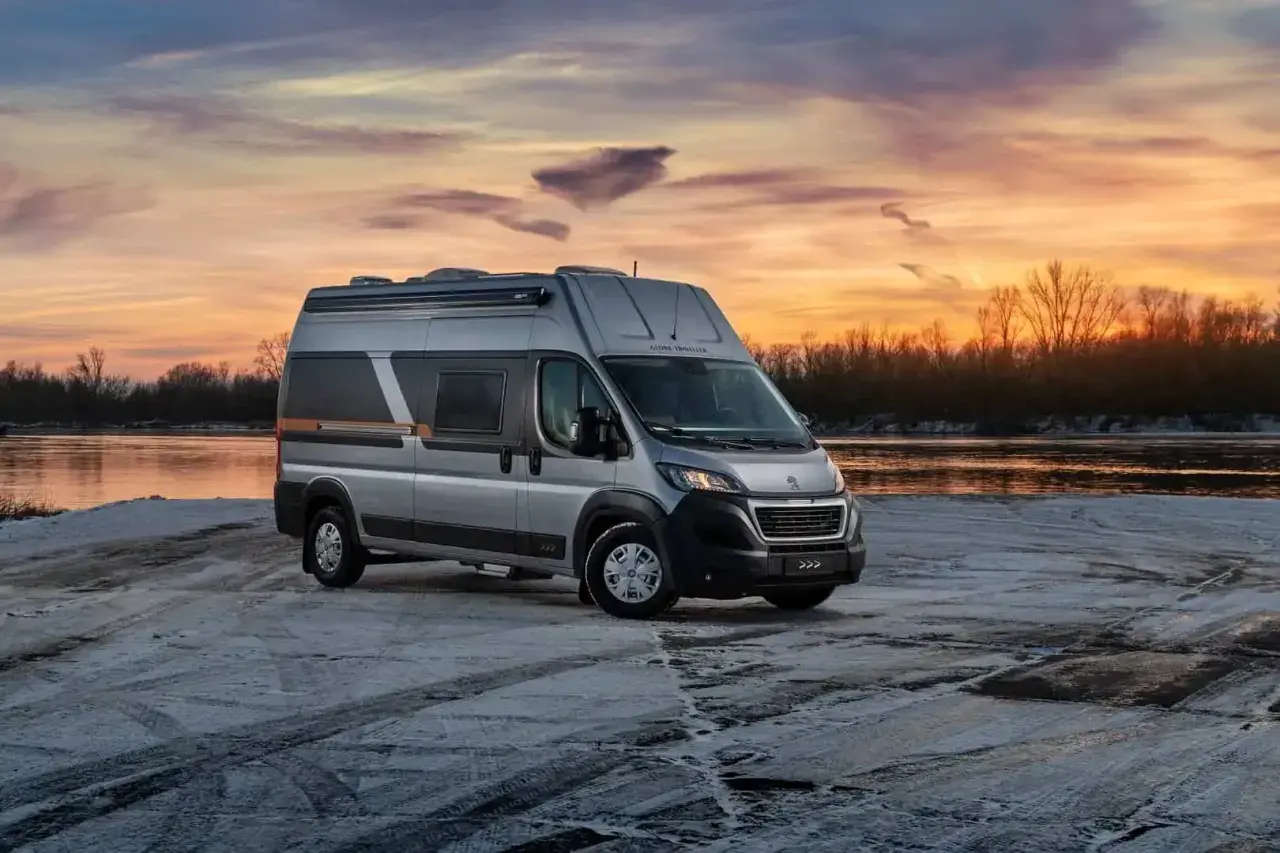 Srebrny kamper Globe-Traveller na tle zachodzącego słońca nad rzeką. Idealny, jaki kamper dla 2 osób na zimową podróż.