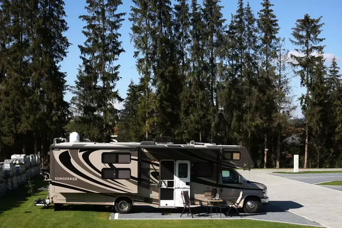 Kamper Sunseeker zaparkowany na campingu Gorący Potok, otoczony wysokimi drzewami.