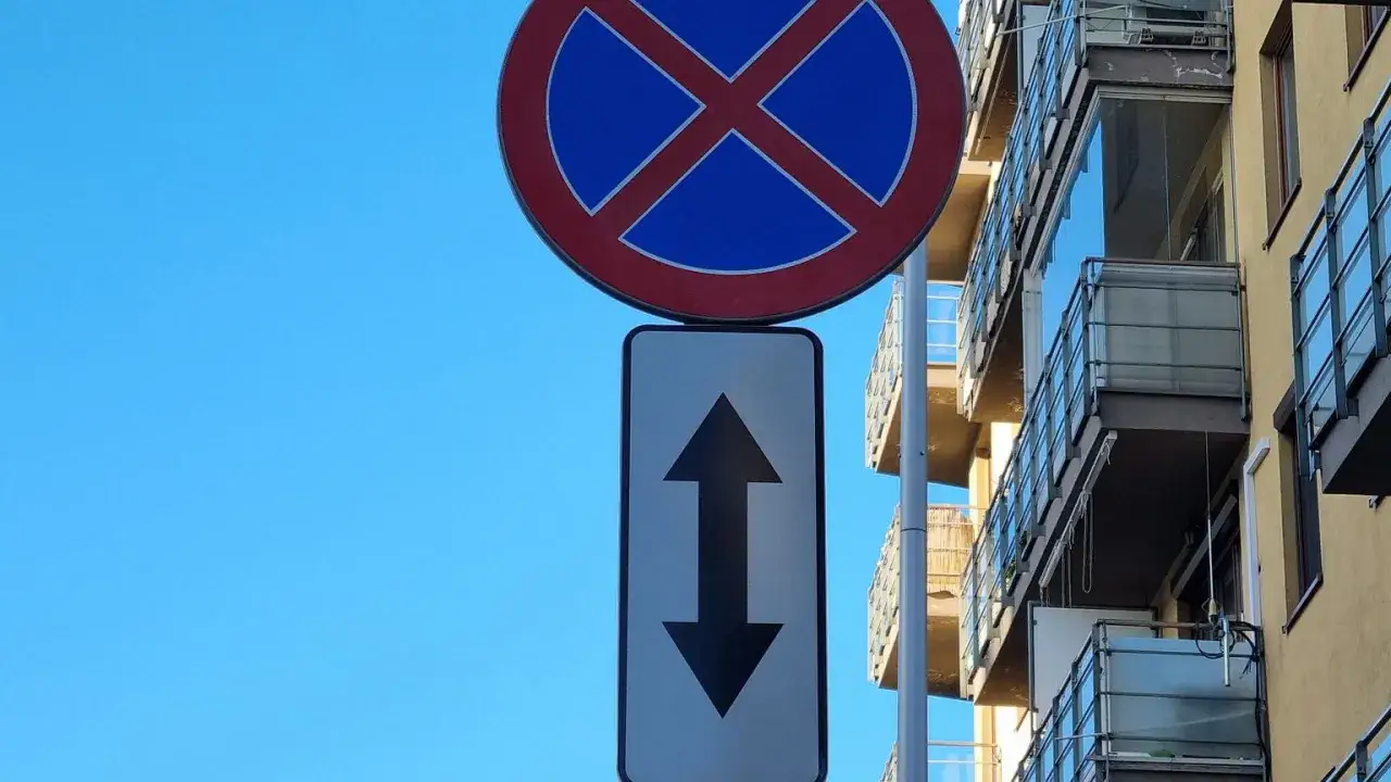 Znak zakazu zatrzymywania się i postoju, z tabliczką wskazującą, że zakaz obowiązuje na odcinku w obu kierunkach. To miejsce, gdzie nie można się zatrzymywać.