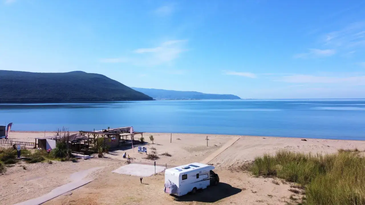 Kamper na piaszczystej plaży z widokiem na spokojne morze i góry. To jedno z najpiękniejszych miejsc w Grecji kontynentalnej.